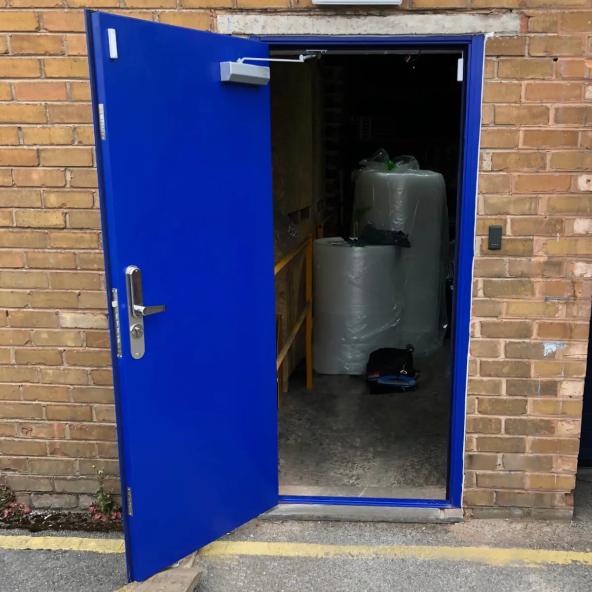 Puerta metálica azul para acceso industrial, imagen referencial